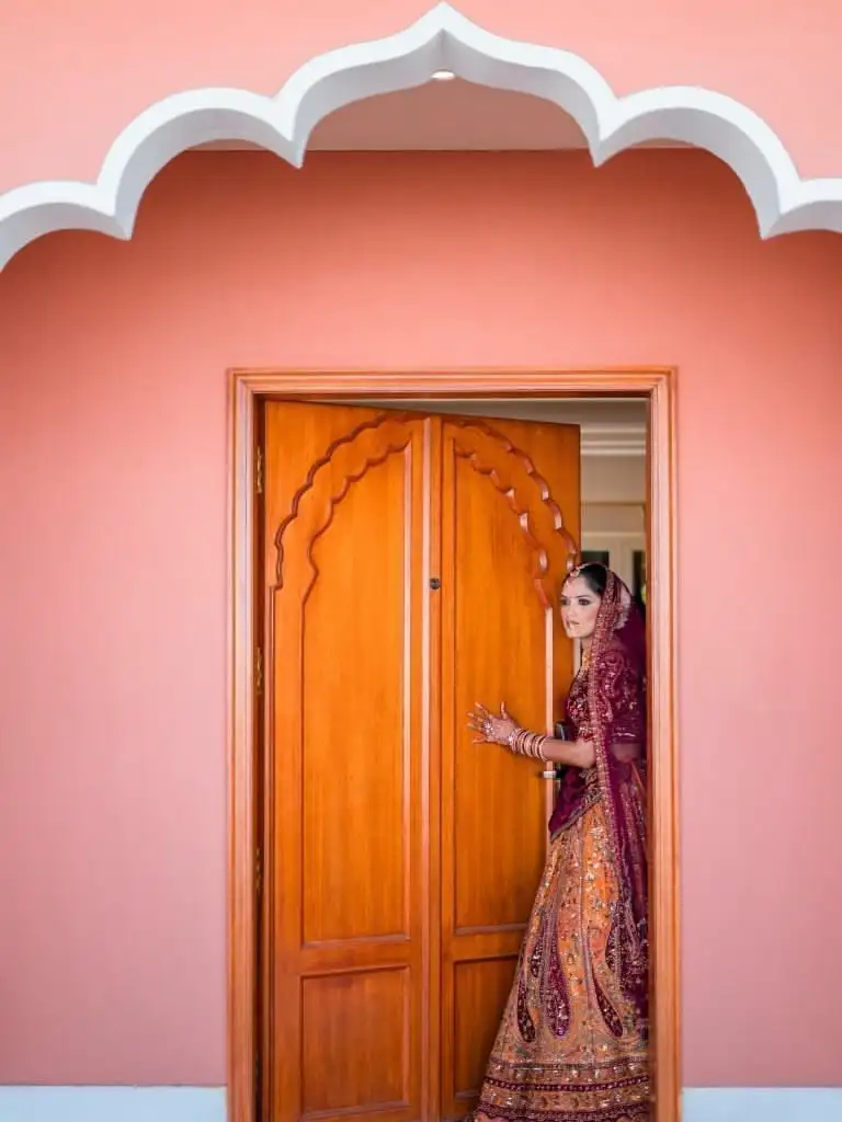 A bride steps out of a room for wedding photography in AbuDhabi, captured in a candid moment, radiating beauty and excitement for her special day.