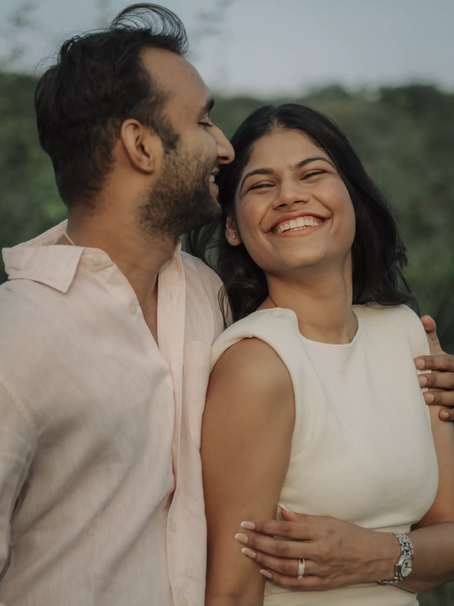 A couple shares joyful moments during their pre-wedding shoot, laughing and enjoying each other's company in a beautiful outdoor setting.